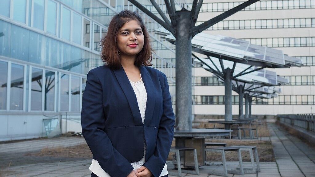 Female student standing in front of solar pabels at a university campus