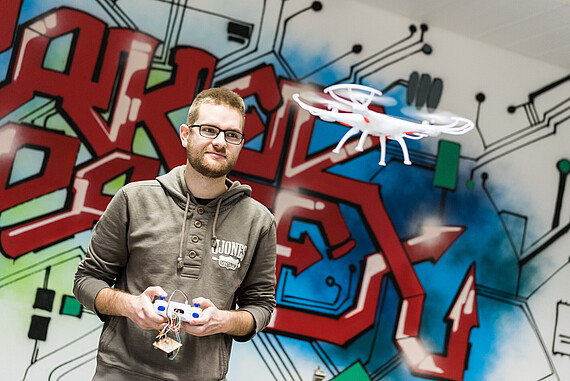
                                Makerspace und Drohnenprojekt, Student vor bunter Wand
                            