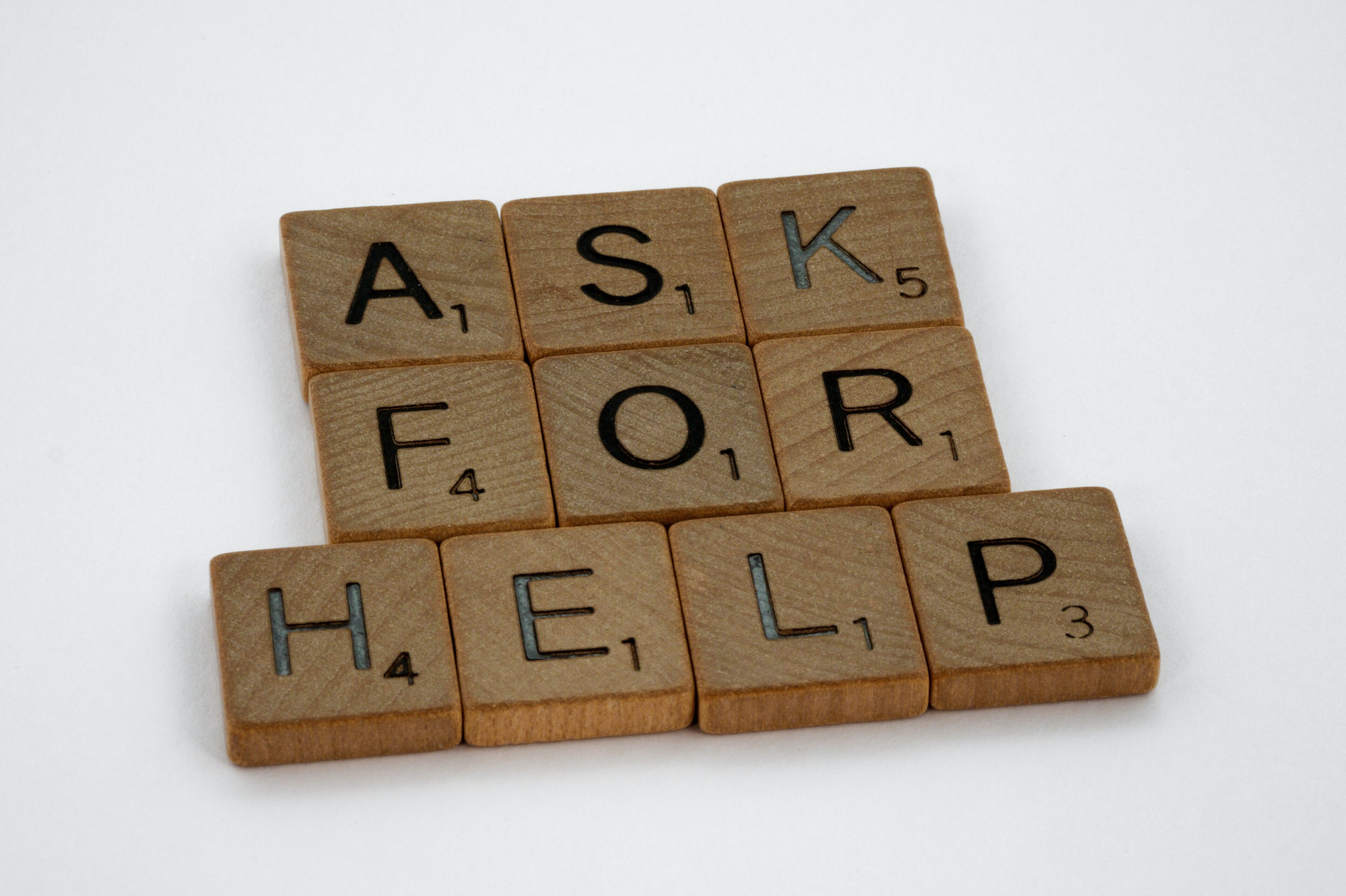 Das Bild zeigt Scrabble-Steine, die die Worte "Ask for Help" ergeben.