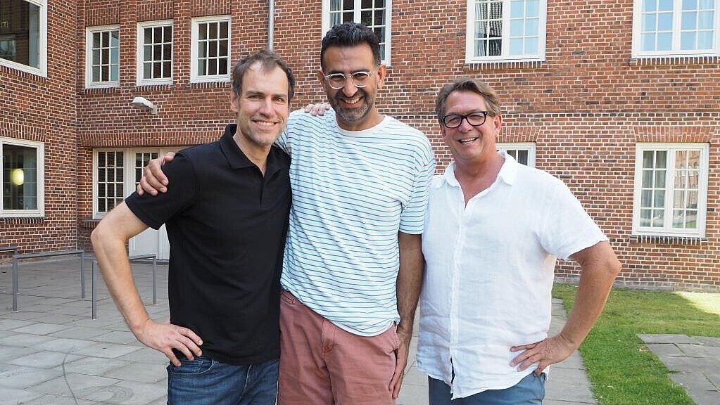 Three professors standing in front of a university building