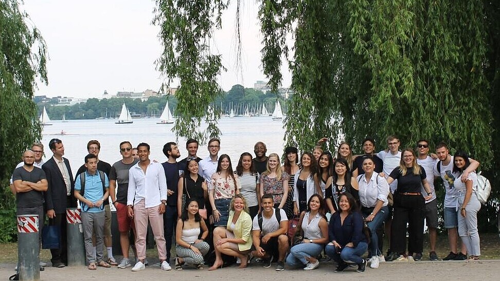 Group of students posing for a photo in front of a lake