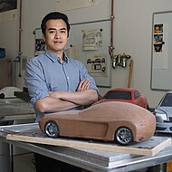 
                                Male student posing with model cars
                            