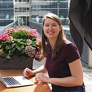 Female student sitting with a laptop outside on campus